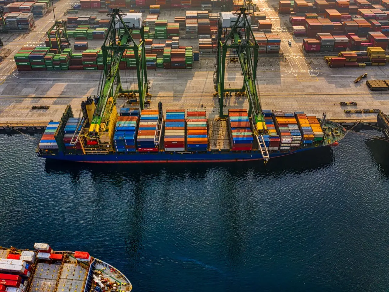 Aerial view of a container ship being loaded by gantry cranes at a busy port