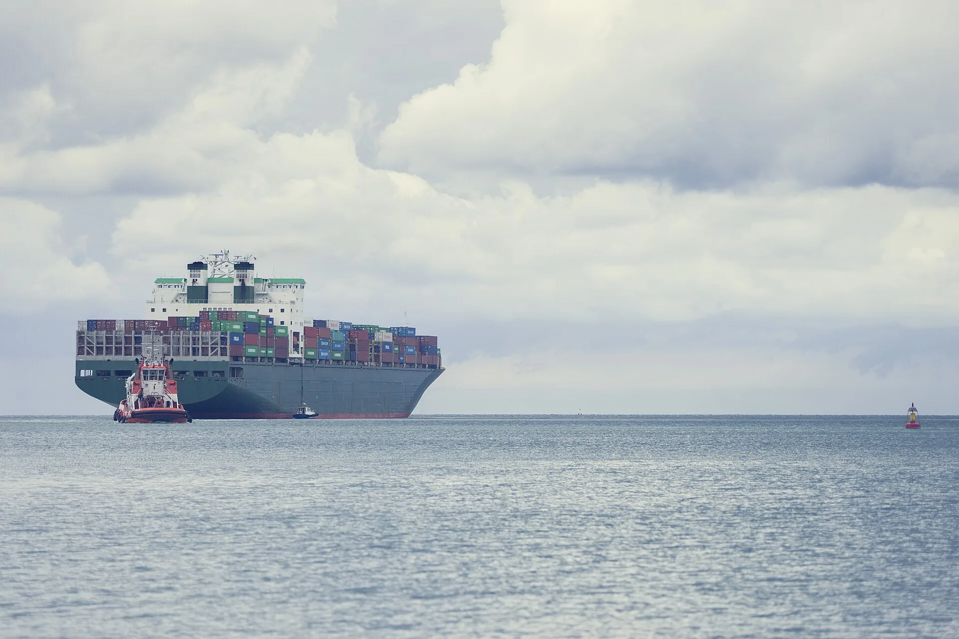Container ship arriving at port with tug boat